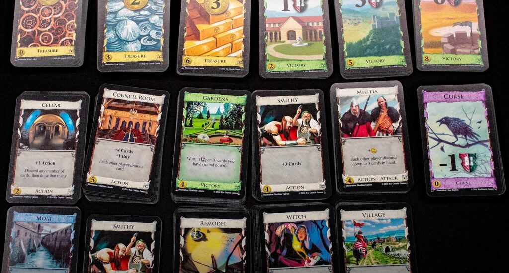 different Dominion cards on the table: Smithy, Militia, Curse, Council Room, Cellar, Moat and others